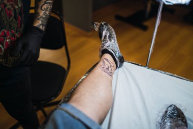 Dövmeci bacağına dövme yapıyor.