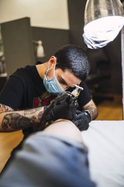 Dövme stüdyosunda dövme yapan adam.