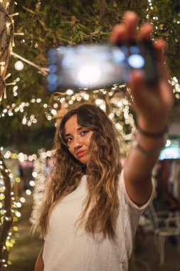 Genç ve güzel bir kadın akıllı telefondan selfie çekiyor.