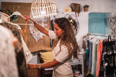 Genç ve güzel bir kadın mağazadan elbise seçiyor.