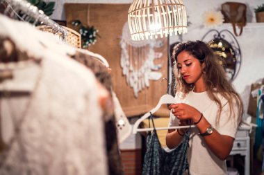 Mağazada kıyafet seçen genç bir kadın..