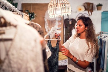 Moda mağazasında kıyafet seçen genç bir kadın.