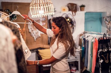Güzel genç bir kadın mağazadan kıyafet seçiyor.