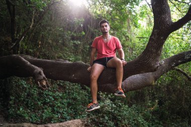 Genç adam bir ağaçta oturuyor