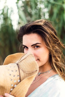 Omzunda hasır şapkası olan genç bir kadın.