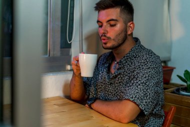 Genç adam evde kahve içme portresi