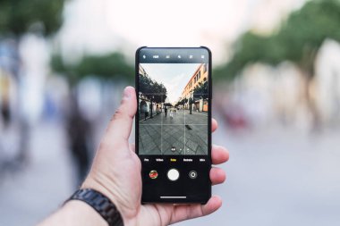 Şehrin arka planında el ele tutuşan cep telefonu