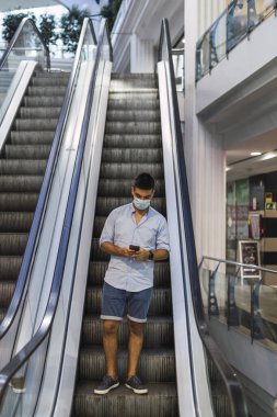 Asansörde cep telefonu olan Asyalı bir adam.