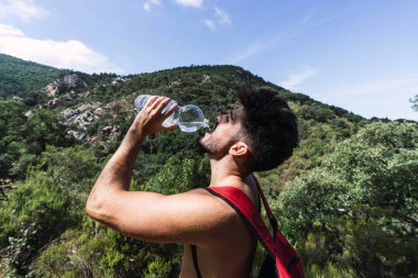 Dağ zirvesinde bir şişe suyu olan yakışıklı bir adam..