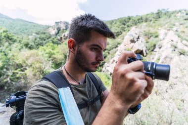 Genç fotoğrafçı dağlarda fotoğraf çekiyor. Adam kendi doğasında resim çekiyor..