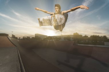 Kaykaycı gün doğumunda bir kaykaycının üzerinden atlıyor..