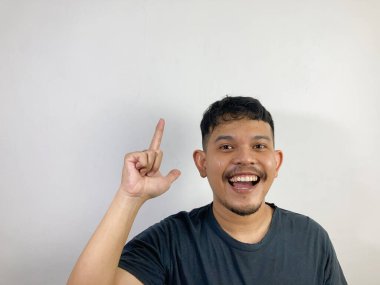 Genç Asyalı bir adam gülümseyen bir yüz ve işaret eden bir işaret.