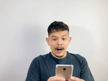 Genç Asyalı bir adam akıllı telefona bakarken şok oldu.