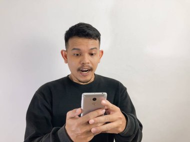 Genç Asyalı bir adam akıllı telefona bakarken şok oldu.