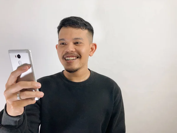 Joven Asiático Hombre Sonriendo Mientras Mira Teléfono Inteligente — Foto de Stock