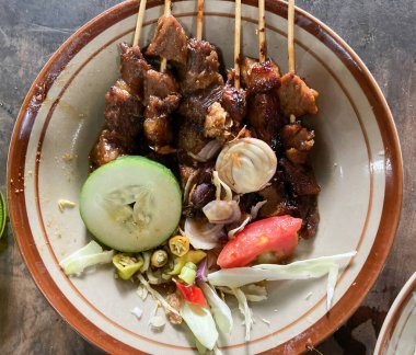 Sate Daging Sapi ya da biftek satay, tabakta soğan, biber, soya sosu ve domates ile servis edilir..