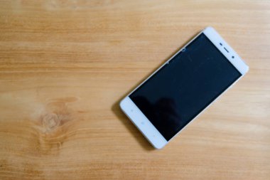 Ahşap arka planda bir akıllı telefon.