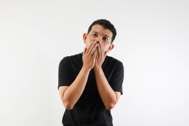 Yetişkin bir Asyalı, elleri ağzını kapatırken şok olmuş bir ifade sergiliyor.