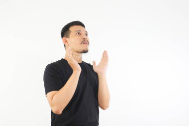 Asyalı bir adam şok olmuş yüzünü gösteriyor ve yukarı bakıyor.