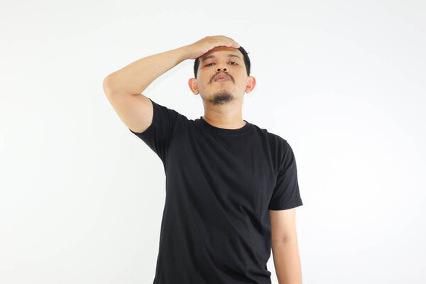 Asian man wearing black shirt, looking stressed expression and touching his forehead