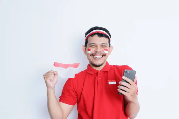 Pria Asia Muda Yang Tersenyum Memegang Ponsel Dan Bendera Indonesia — Stok Foto