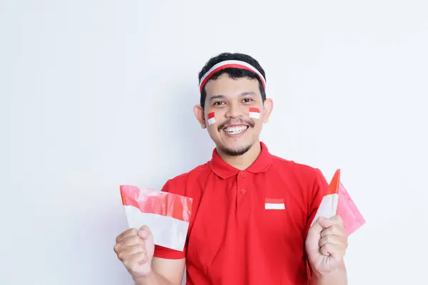 stock image Indonesian man clenched fist, carrying red and white flag, showing excitement when celebrating independence day