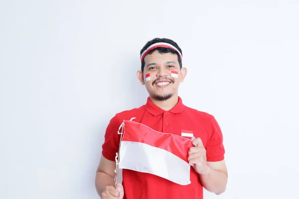 stock image Indonesian man clenched fist, carrying red and white flag, showing excitement when celebrating independence day