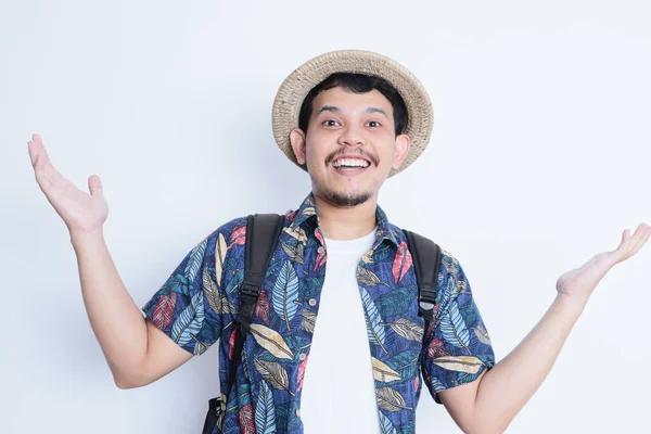 stock image portrait of a young man wearing a beach suit smiling and giving open hands gesture at the camera. vacation and traveling concept