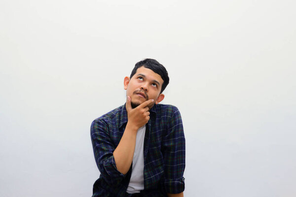 Adult Asian man wearing casual shirt showing thinking gesture, doubtful expression
