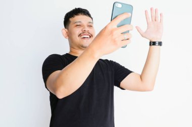 Asyalı bir adam görüntülü arama yapıyor ve mutlu bir ifade sergiliyor.