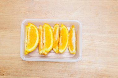 Tahta bir masada plastik bir kabın içinde sunkist portakal meyvesi.