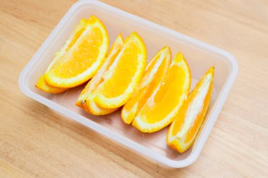 Tahta bir masada plastik bir kabın içinde sunkist portakal meyvesi.