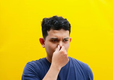 Burnunu kapatan Asyalı genç bir adamın portresi. Stüdyo çekimi