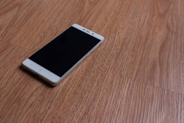 Ahşap arka planda bir akıllı telefon.