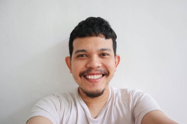 Asyalı genç bir adam gülümsüyor.