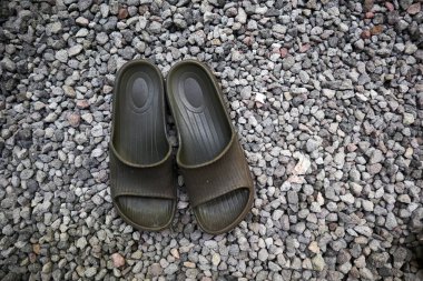 Küçük kayalardan ya da çakıllardan oluşan arka planı olan sandaletler