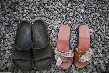 Küçük kayalardan ya da çakıllardan oluşan arka planı olan sandaletler