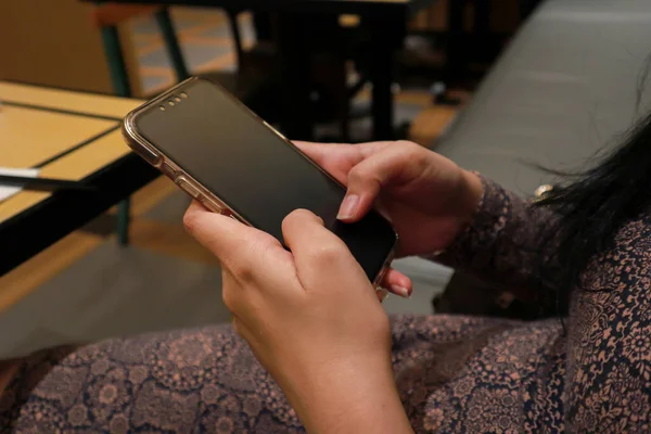 female hand holding smartphone in a restaurant. selective focus
