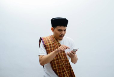 Asyalı Müslüman adam akıllı telefonuna bakarken şaşkın bir şekilde yüzünü gösteriyor.