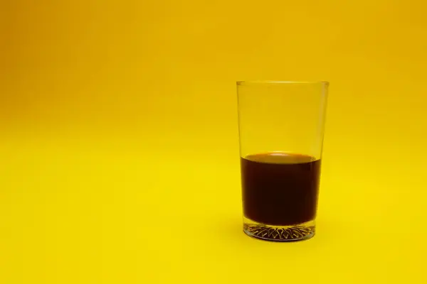 a glass of coffee isolated on yellow background