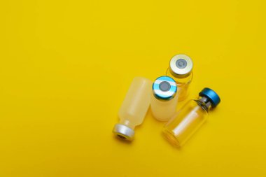 Sarı arka planda izole edilmiş birkaç şişe enjeksiyon ilacı.