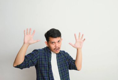 Korkmuş bir ifade sergileyen ve ellerini kaldıran Asyalı genç bir adamın portresi. Yüz ifadeleri, endişe ve zihinsel sağlık