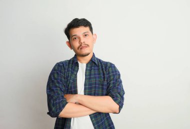 Asyalı genç bir adamın portresi somurtkan ve hayal kırıklığına uğramış bir yüz ifadesi, beyaz bir arka planda izole edilmiş.