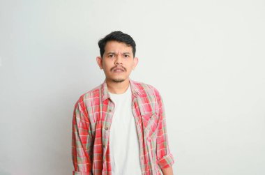 Asyalı genç bir adamın portresi somurtkan ve hayal kırıklığına uğramış bir yüz ifadesi, beyaz bir arka planda izole edilmiş.