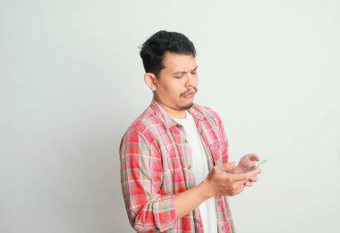 Asyalı adam cep telefonunu üzgün bir ifadeyle tutuyor.