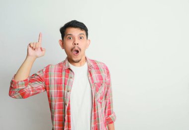 Asyalı adamın şok olmuş yüzü elleriyle bir şey gösteriyor.