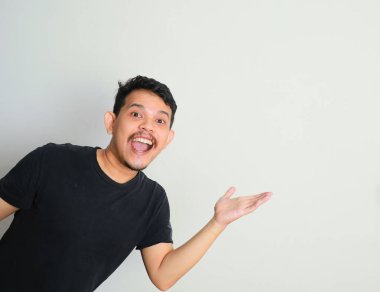 Neşeli Asyalı genç adam beyaz arka planı sanki bir şey tutuyormuş, tavsiye ediyormuş, bir şey gösteriyormuş gibi kaldır.