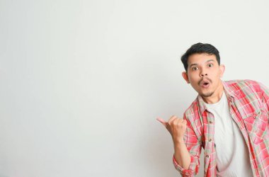 Asyalı bir adam gülümser ve eliyle bir şeye işaret eder.