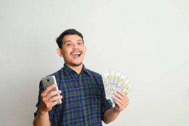 Gülümseyen bir adam cep telefonu ve elinde bir sürü para
