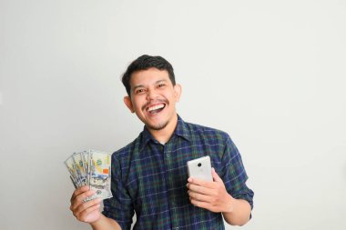 Gülümseyen bir adam cep telefonu ve elinde bir sürü para